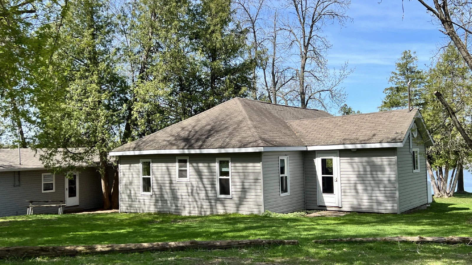 Pigeon Lake Resort Cottage two.&nbsp; Exterior view of a cottage surrounded by trees and grass near the lake.